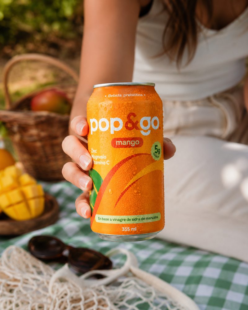 Lata Pop&Go Mango en mano en un picnic